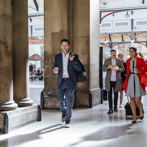 People carrying coffee leaving a train station