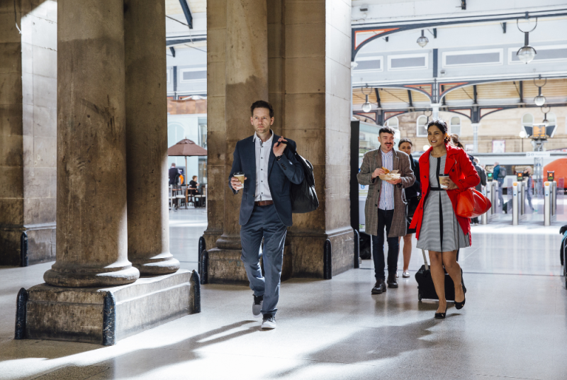 People carrying coffee leaving a train station